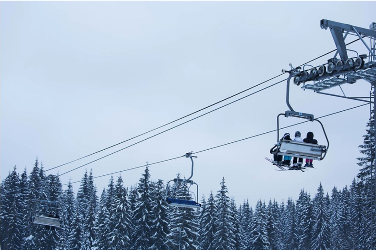 landscape shot of three people using a gondola in snow